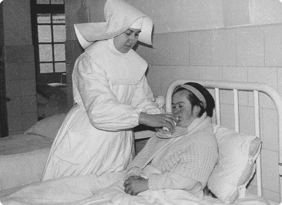 Fotografía histórica de una Hermana Hospitalaria atendiendo a una paciente