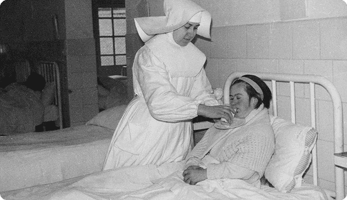 Fotografía histórica de una Hermana Hospitalaria atendiendo a una paciente